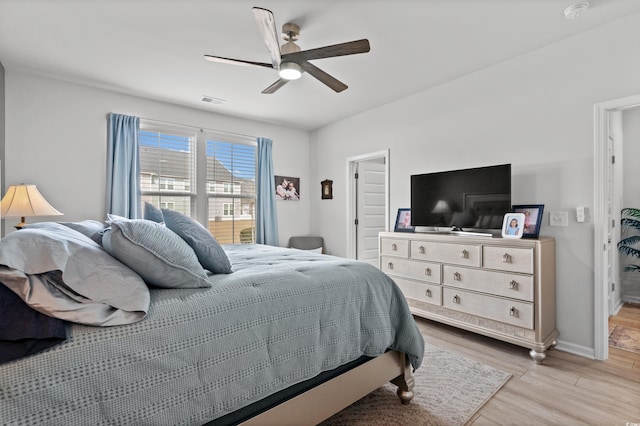 bedroom with a ceiling fan, baseboards, visible vents, and wood finished floors