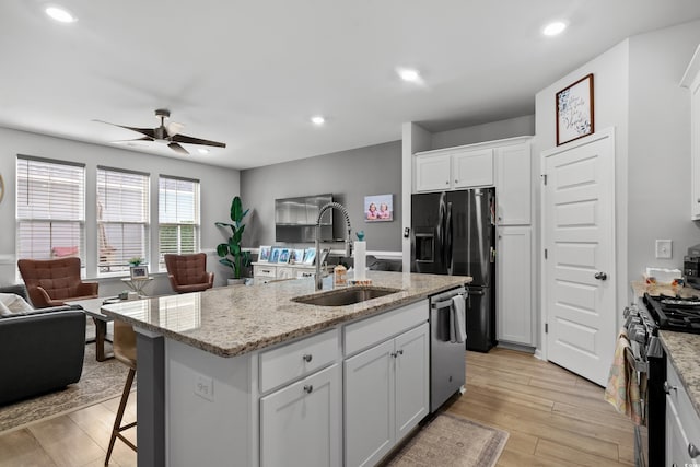 kitchen featuring ceiling fan, a sink, white cabinets, black appliances, and open floor plan