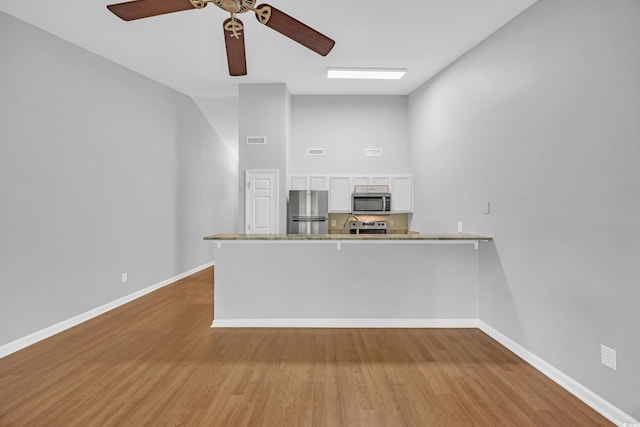 1260 White Tree Ln Unit F, Myrtle Beach, SC 29588 - kitchen featuring a peninsula, wood finished floors, white cabinets, a ceiling fan, and stainless steel appliances