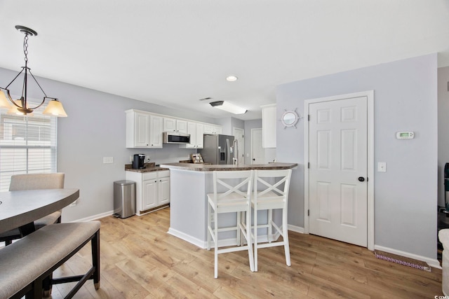 1097 Stoney Falls Blvd, Myrtle Beach, SC 29579 - kitchen with appliances with stainless steel finishes, white cabinets, light wood finished floors, baseboards, and a breakfast bar