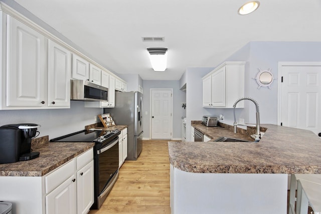 1097 Stoney Falls Blvd, Myrtle Beach, SC 29579 - kitchen with stainless steel appliances, a sink, light wood finished floors, dark countertops, and white cabinets