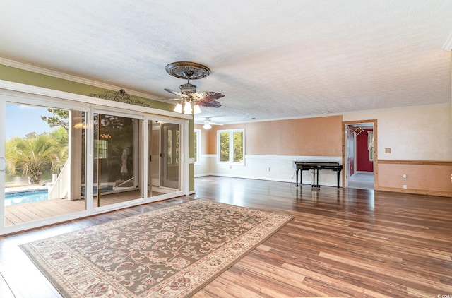 128 Causey St, Myrtle Beach, SC 29577 - unfurnished living room with ornamental molding, ceiling fan, a wainscoted wall, wood finished floors, and a textured ceiling