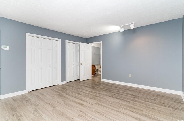 128 Causey St, Myrtle Beach, SC 29577 - unfurnished bedroom featuring multiple closets, baseboards, light wood-style floors, and a textured ceiling