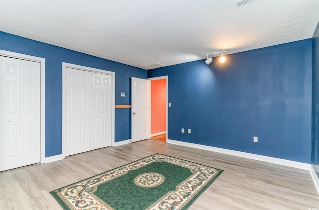 128 Causey St, Myrtle Beach, SC 29577 - unfurnished bedroom with wood finished floors, multiple closets, baseboards, track lighting, and a textured ceiling