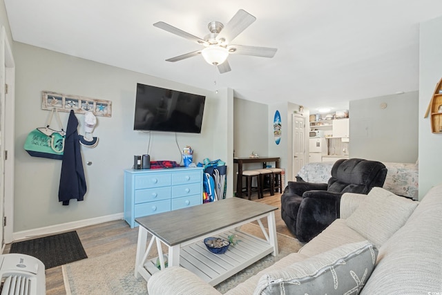 living room featuring ceiling fan, light wood-type flooring, and baseboards