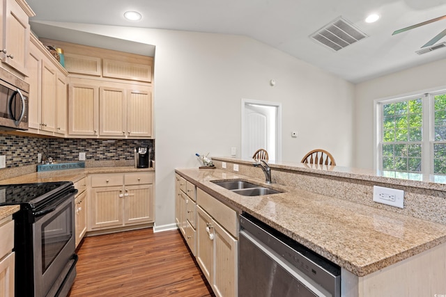 kitchen featuring a sink, dark wood finished floors, stainless steel appliances, lofted ceiling, and visible vents