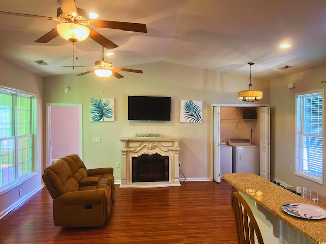 living area with a fireplace with raised hearth, visible vents, dark wood-style floors, and washer and clothes dryer
