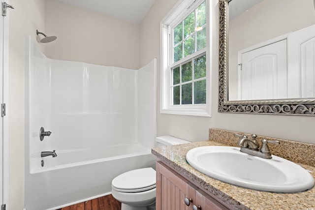 bathroom with vanity, washtub / shower combination, wood finished floors, and toilet