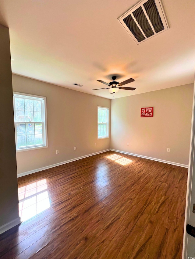 spare room with a ceiling fan, baseboards, visible vents, and dark wood-type flooring