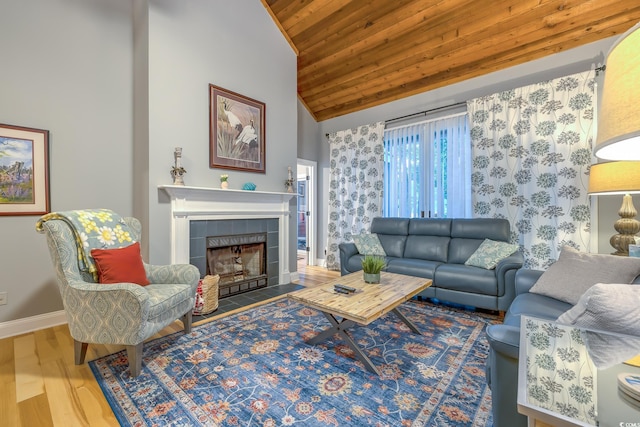 living area featuring wood finished floors, baseboards, wooden ceiling, a tile fireplace, and vaulted ceiling