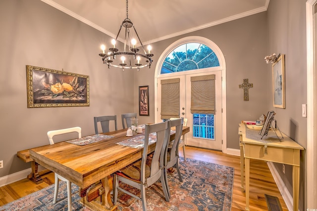 dining area with ornamental molding, french doors, wood finished floors, and a chandelier