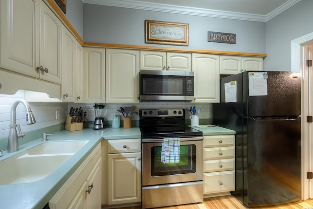kitchen with crown molding, appliances with stainless steel finishes, a sink, light countertops, and decorative backsplash