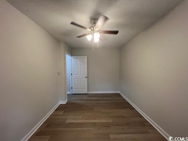 spare room featuring baseboards, a ceiling fan, dark wood finished floors, and a textured ceiling