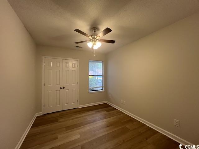 spare room with baseboards, dark wood finished floors, and ceiling fan