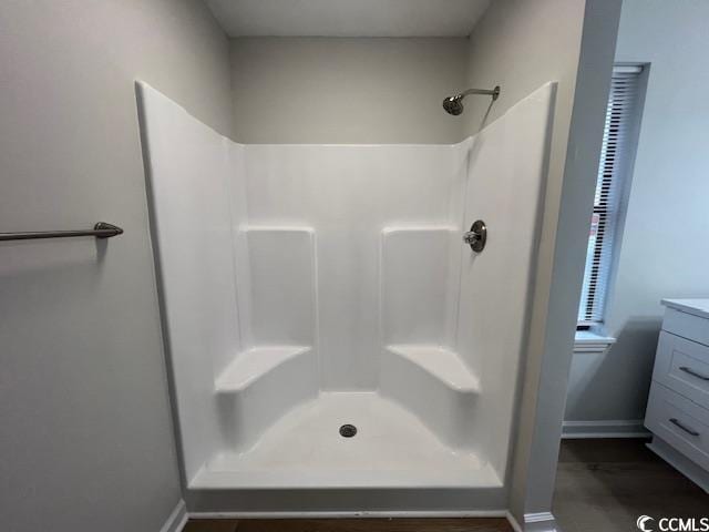 bathroom with baseboards, walk in shower, and vanity