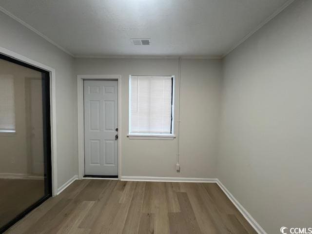 interior space featuring crown molding, baseboards, wood finished floors, and visible vents