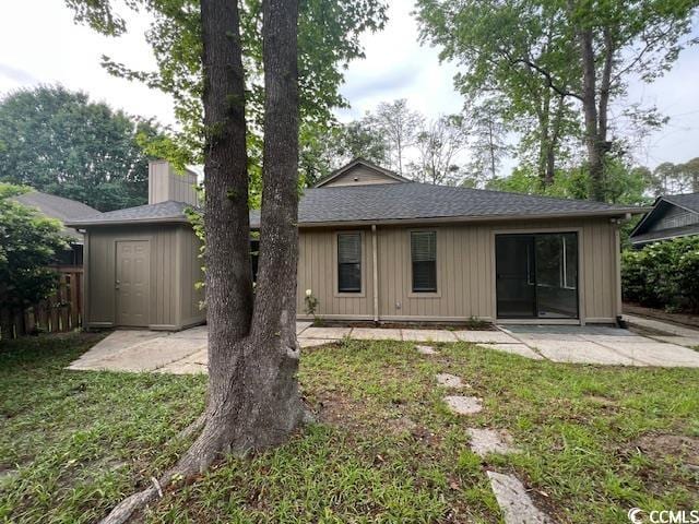 back of house with a patio, roof with shingles, fence, and a yard