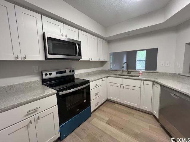 116 Hickory Dr, Conway, SC 29526 - kitchen with light wood finished floors, a sink, white cabinetry, light countertops, and appliances with stainless steel finishes