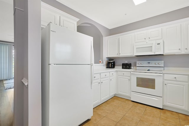 kitchen featuring white appliances, light countertops, white cabinets, arched walkways, and light tile patterned floors