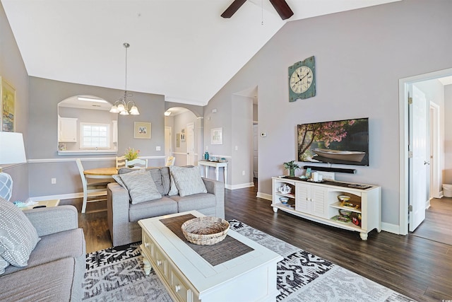 living area with arched walkways, wood finished floors, baseboards, high vaulted ceiling, and ceiling fan with notable chandelier
