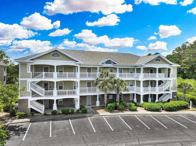 view of property featuring uncovered parking and stairway