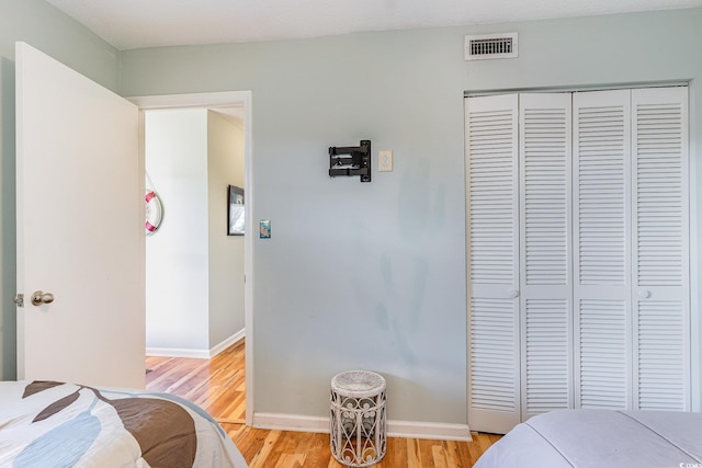 bedroom featuring light wood finished floors, a closet, and baseboards