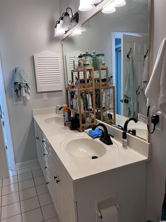 bathroom with a sink, baseboards, tile patterned flooring, and double vanity