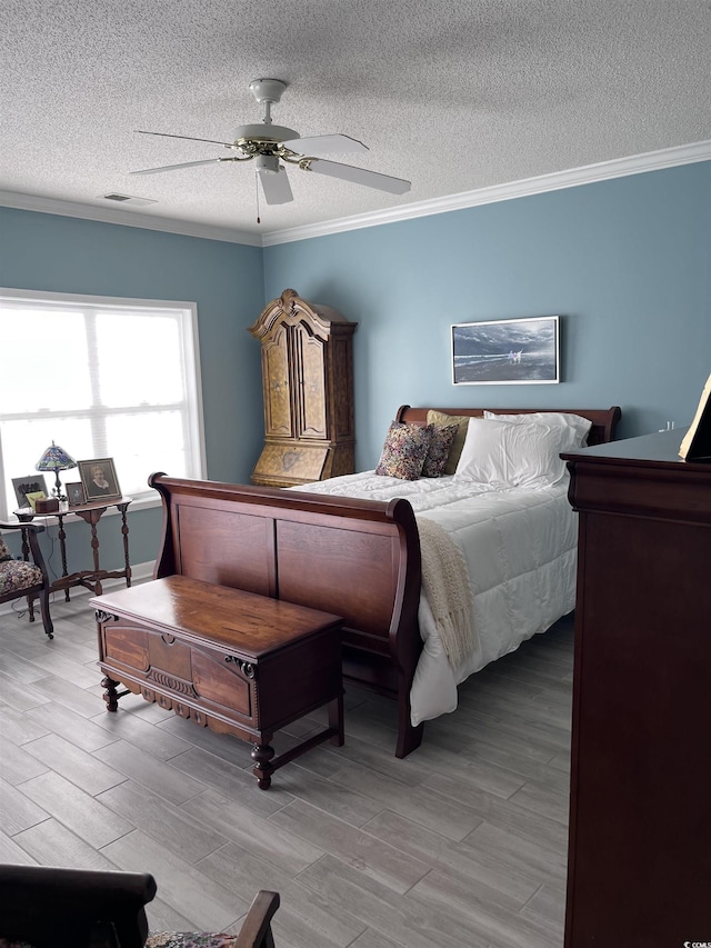 bedroom with crown molding, a ceiling fan, a textured ceiling, and wood finished floors