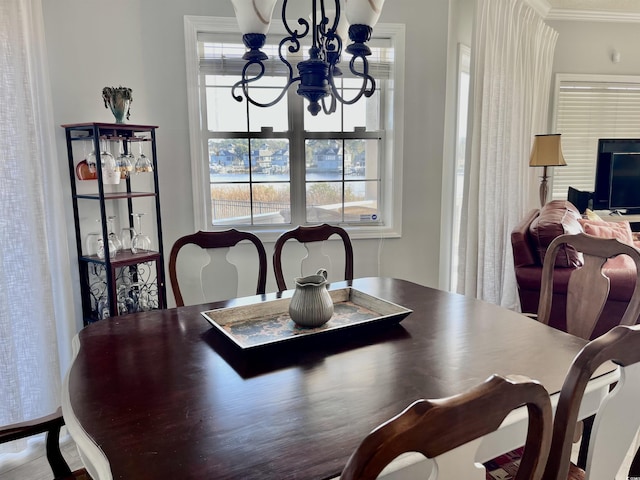 dining area with an inviting chandelier, plenty of natural light, and ornamental molding