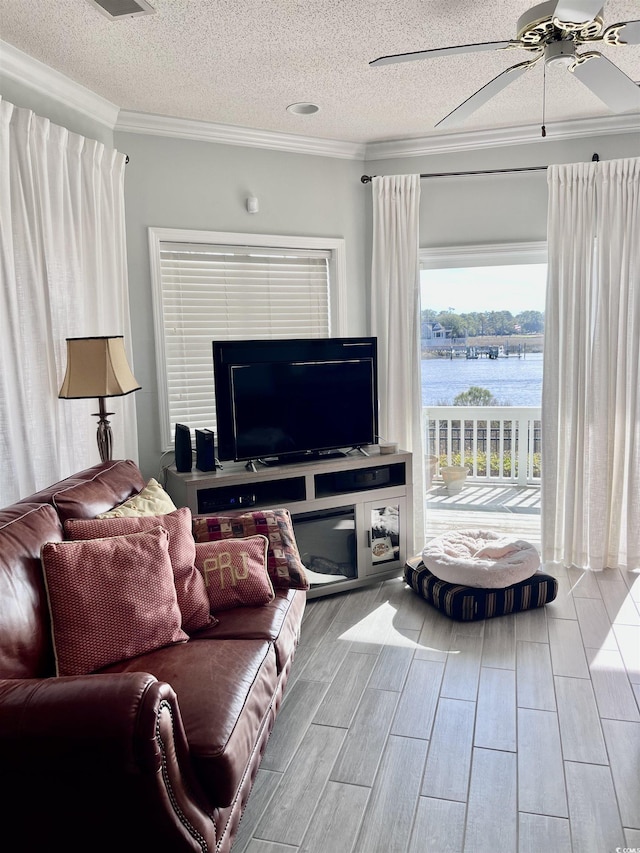 living room featuring a textured ceiling, ornamental molding, a ceiling fan, and wood finished floors