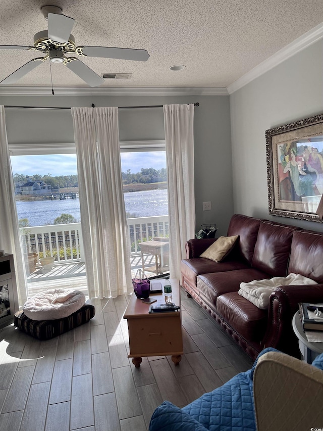 living room with crown molding, ceiling fan, a textured ceiling, a water view, and visible vents
