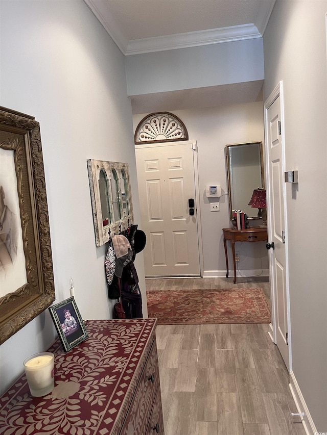 entrance foyer featuring crown molding, baseboards, and wood finished floors