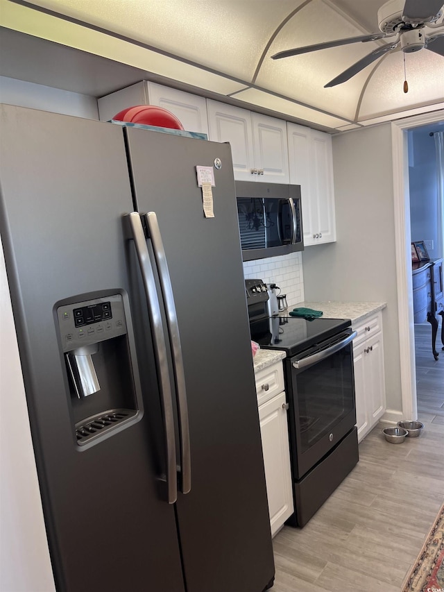 kitchen featuring appliances with stainless steel finishes, white cabinets, decorative backsplash, and a ceiling fan