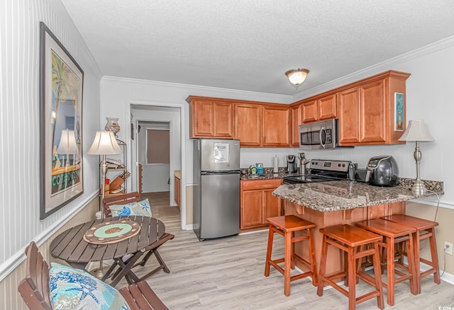 4516 Seaview St Unit 135, North Myrtle Beach, SC 29582 - kitchen with stainless steel appliances, brown cabinetry, a peninsula, light wood-style flooring, and a textured ceiling