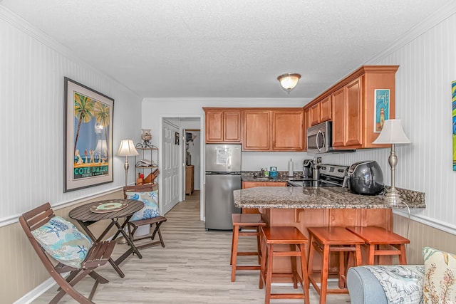 4516 Seaview St Unit 135, North Myrtle Beach, SC 29582 - kitchen featuring appliances with stainless steel finishes, ornamental molding, light wood-style flooring, a peninsula, and stone counters