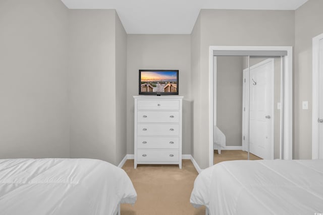 bedroom featuring baseboards, light colored carpet, and a closet