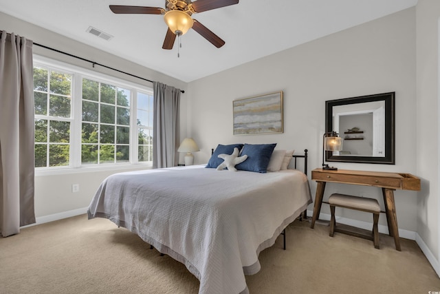 bedroom featuring visible vents, a ceiling fan, baseboards, and light colored carpet