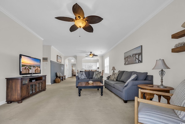 living room featuring light colored carpet, a ceiling fan, baseboards, and ornamental molding