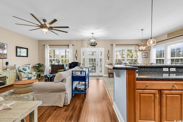 kitchen with open floor plan, brown cabinets, a ceiling fan, light wood-style flooring, and decorative light fixtures