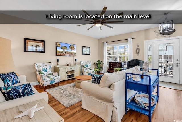 living area featuring ceiling fan with notable chandelier and wood finished floors