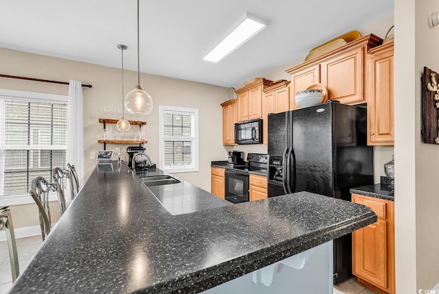 kitchen with pendant lighting, a peninsula, dark countertops, a sink, and black appliances