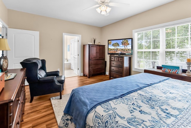bedroom with light wood-style floors, a ceiling fan, and connected bathroom