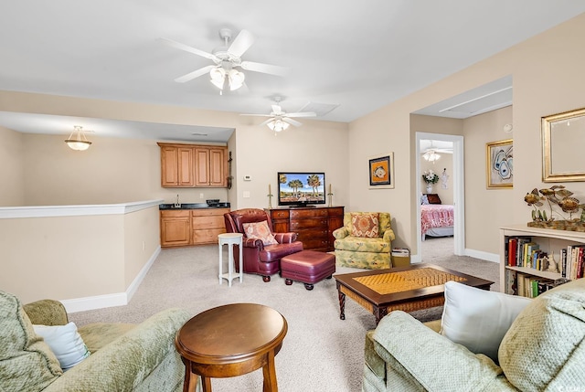 living room with baseboards, ceiling fan, and light carpet