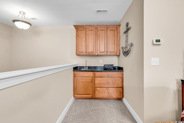 bar featuring visible vents, light carpet, baseboards, a sink, and wet bar