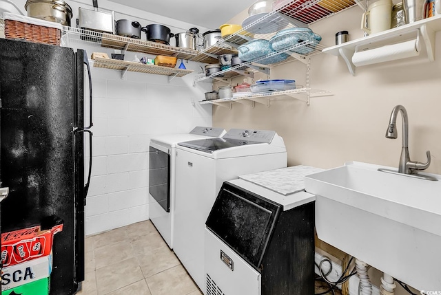 laundry room with laundry area, a sink, light tile patterned floors, and separate washer and dryer