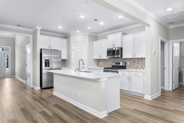 kitchen with appliances with stainless steel finishes, a sink, light wood finished floors, light countertops, and visible vents