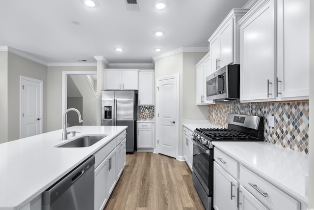 kitchen featuring crown molding, recessed lighting, light countertops, a sink, and stainless steel appliances