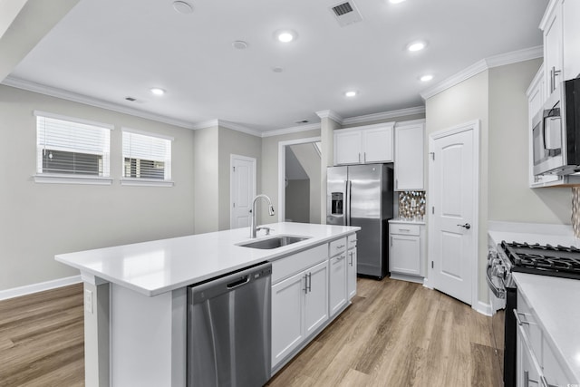 kitchen with visible vents, light wood-style floors, an island with sink, a sink, and stainless steel appliances