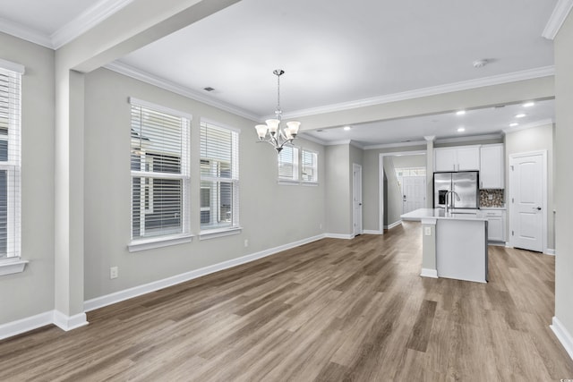 kitchen with baseboards, an inviting chandelier, stainless steel fridge, and light wood-type flooring