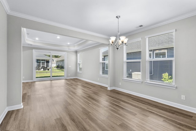 empty room featuring crown molding, a notable chandelier, recessed lighting, baseboards, and wood finished floors